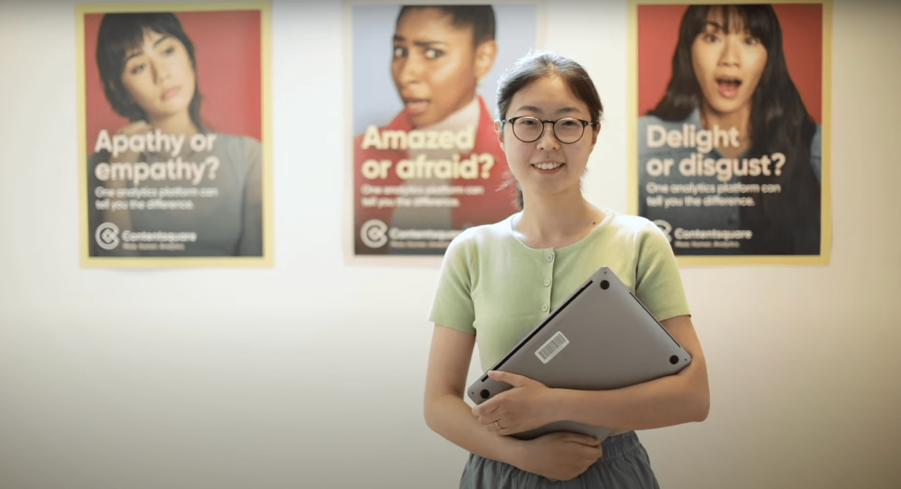 a content square employee with her laptop standing in front of content square posters